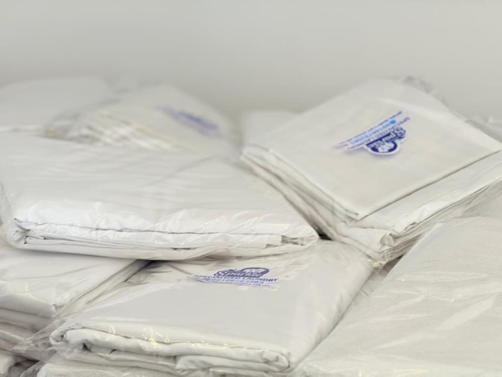 Neatly packaged white linens with Garment Sparkle branding